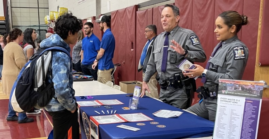 Pictured: Member sof the NYS Police Department speaking with a student at the job fair
